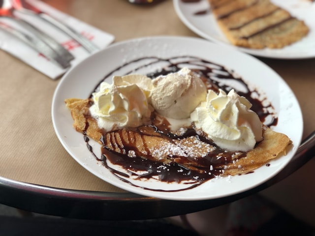 crepe topped with chocolate sauce, whipped cream, and ice cream