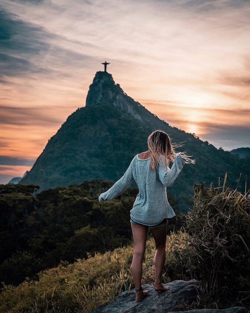 Bree stands on a rock in Rio de Janeiro with Christ the Redeemer statue in the background