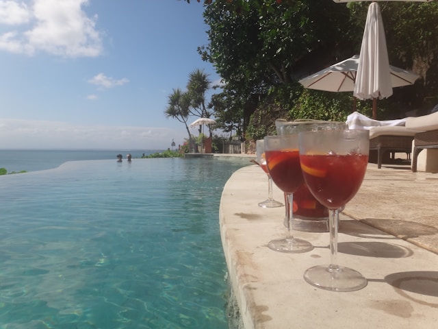 2 glasses and a pitcher of sangria by an infinity pool looking out over the ocean