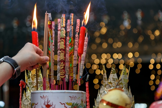 a person's hand lights incense to celebrate Chinese New Year