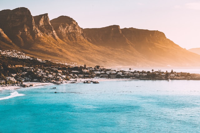 Cape Town coast at golden hour. The mountains are gold above the bright blue ocean.