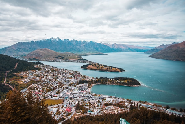 aerial view of Queenstown with the buildings and town below, the lake, and mountains in the distance