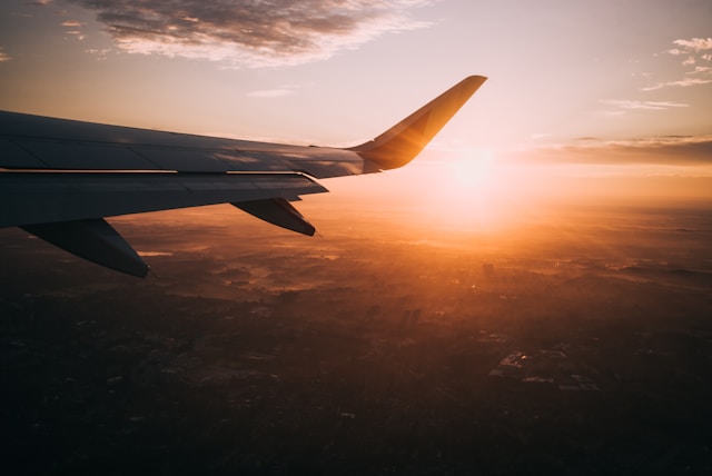the wing of an airplane at sunset from thousands of feet of elevation