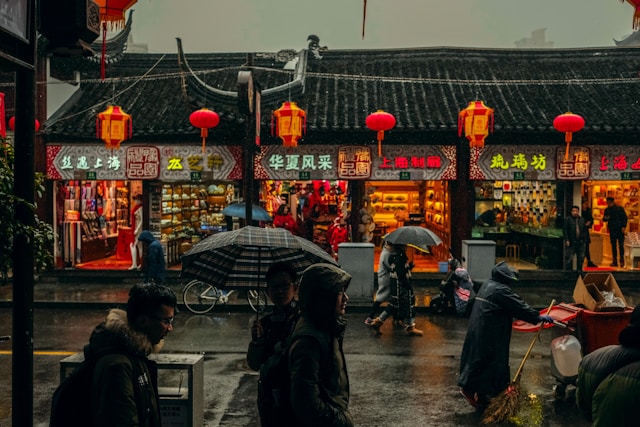 people walk with umbrellas on the street of Shanghai on a dark, rainy day
