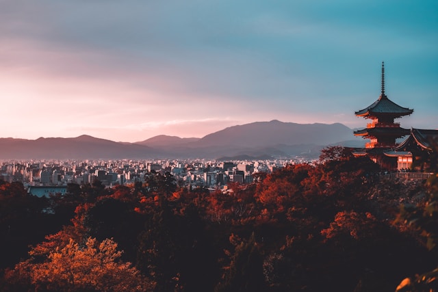 a temple in Kyoto Japan at sunset with a view over the trees and city