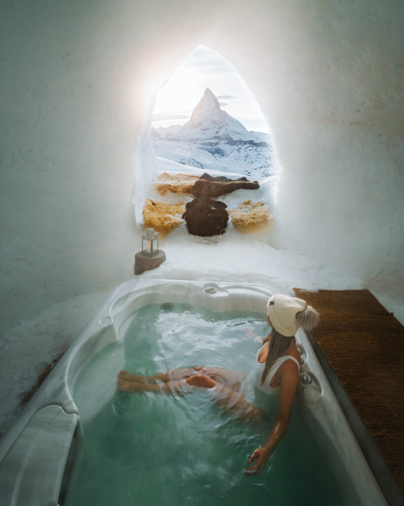 Bree sits in a jacuzzi in an igloo in Switzerland with a window looking out at the Matterhorn