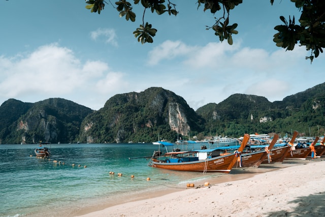 fishing boats are on the beach with lush mountains in the background