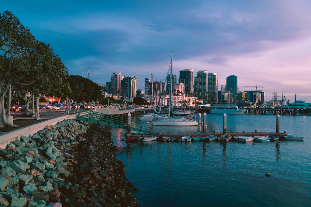 Twilight photo of San Diego marina with skyline and docked boats, capturing urban tranquility.