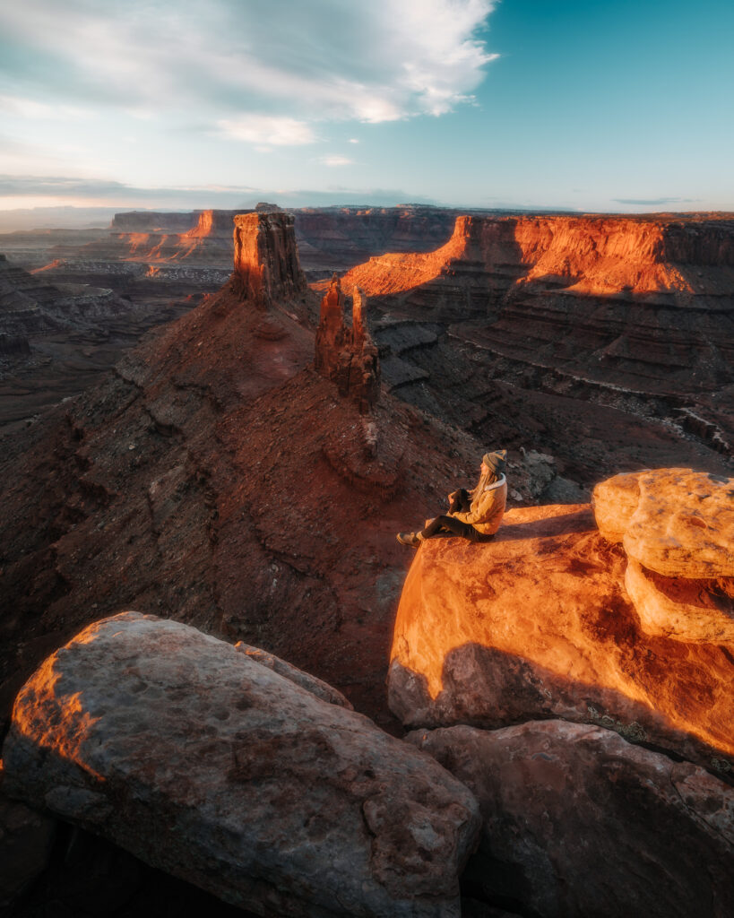 Bree sits in the sun on the edge of a cliff in Utah